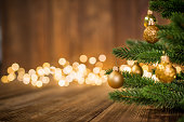 Fir Tree decorated with christmas balls on rustic wood and sparkles light backgorund