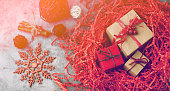 Christmas dark aged background under a cement table with red decorations, wrapped in a wrapper with ribbons, gifts, snowflakes, rattan balls and corrugated cut paper of red color