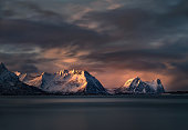 Snowcapped mountain range lightened by the first morning light in Steinfjord, Norway.