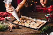 Woman icing gingerbread christmas cookie by son in kitchen