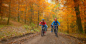Young friends mountain biking in autumn forest