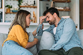 Worried couple talking together in the living room at home.