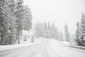 Wide windy highway blizzard thru snow covered forest