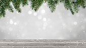 frame from green christmas tree branches and empty wooden table on white blurred background as product display in december holiday season
