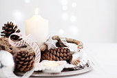 Christmas centerpiece with candles, pine cones, branch and silver decor