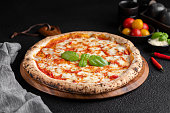 pizza topped with fresh basil, tomato and cheese on top of wooden platter