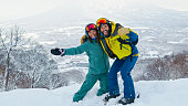 Two Snowboarders Hugging and Grinning at Camera with Mt Yotei in Distance