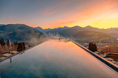 Young woman relaxing in the infinity pool with a nature landscape view in Dolomites, Italy