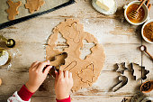 Chils cutting dough to make christmas cookies on kitchen counter
