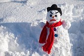 A snowman with a creepy grimace in a hat and scarf.