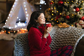 Woman enjoys the scent of coffee during Christmas at home