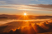 Beautiful Sunrise View on Foggy Forest in Tuscany, Italy with Green Hills and Cypress Trees on a Sunny Spring Day