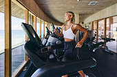 Young female athlete running on treadmill in a gym.