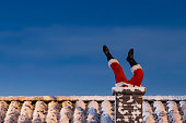 Santa claus stuck in chimney delivering gifts on christmas eve