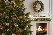 Close-up Of Christmas Tree With Ornaments And Christmas Lights In Living Room With Blurred Background