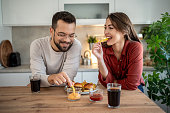 Cheerful couple enjoying fast food meal at home