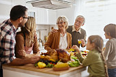 Happy multi-generation family preparing Thanksgiving lunch in the kitchen.