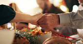 Holding hands, Christmas and prayer with family at dinner table for gratitude, holiday season and love. Worship, spiritual and support with closeup of people in home for festive celebration and trust