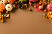Autumn flat lay with pumpkins, pinecone, acorn, leaf, wheat on brown background. Seasonal harvest composition with copy space for fall, Thanksgiving or festive design