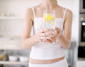 Woman holding glass of water with lemon